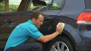 mano limpiando rayon de auto azul