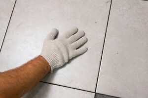 manos instalando ceramica sobre piso limpio