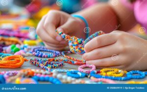 manos tejiendo pulseras de hilo colorido