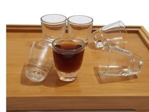 vasos shot de vidrio transparentes sobre mesa madera